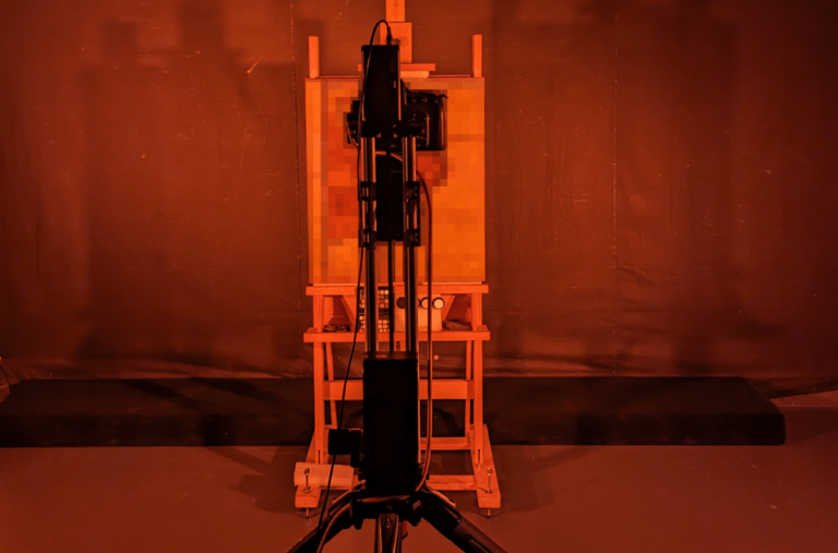 a camera in front of a painting mounted on an easel, the scene is flooded with red light